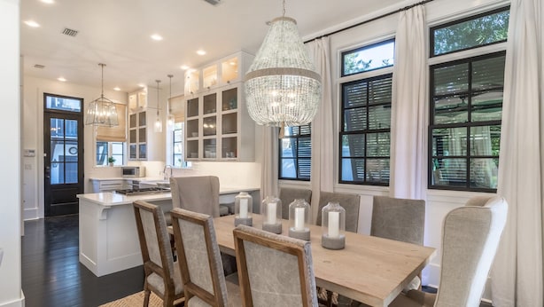 Una cocina moderna con una isla central, iluminación colgante y ventanas amplias.
