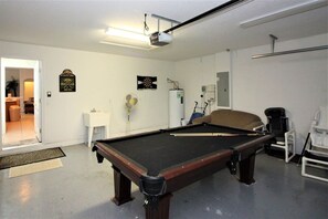 A pool table in a room with white walls, a ceiling-mounted projector, and a door leading to another room. - Beautiful 4 Bedroom Highlands Reserve Pool Home - 924NHD (Davenport)