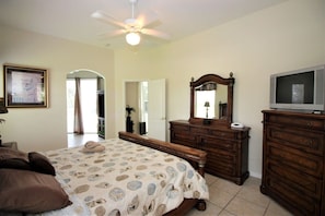 A bedroom with a bed, dresser, television, and ceiling fan. - Beautiful 4 Bedroom Highlands Reserve Pool Home - 924NHD (Davenport)