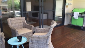 A covered patio with wicker chairs, a small round table, and a green barbecue grill. - So close to the boat ramp and beach for boating enthusiasts and beach goers!!


 (Callala Bay)
