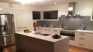 A modern kitchen with a central island, stainless steel appliances, and wooden flooring. - So close to the boat ramp and beach for boating enthusiasts and beach goers!!


 (Callala Bay)
