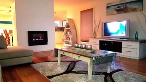 A living room with a fireplace, a television, and a dining table. - So close to the boat ramp and beach for boating enthusiasts and beach goers!!


 (Callala Bay)
