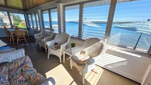 A sunlit room with wicker furniture, large windows, and a view of the water. - Private Level Beachfront, Fenced Yard, Boat Dock,Kayaks,CentralAir, Great Views! (Auburn)
