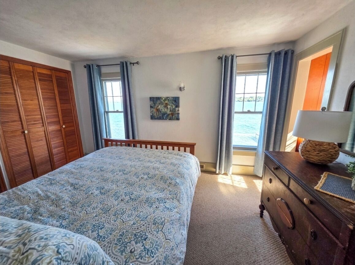 Une chambre avec un grand lit, une commode, une fenêtre avec des rideaux et un tableau au mur.