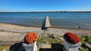 A concrete pier extending into calm water, with two flower arrangements at the shore. - Private Level Beachfront, Fenced Yard, Boat Dock,Kayaks,CentralAir, Great Views! (Auburn)