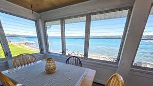 A dining area with a table and chairs, large windows with a view of the water, and a beach sign. - Private Level Beachfront, Fenced Yard, Boat Dock,Kayaks,CentralAir, Great Views! (Auburn)