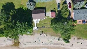 Ett flygbildsbild av ett bostadsområde med hus, en strand och en liten parkeringsplats.