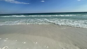 Una playa con huellas en la arena y un cielo despejado.