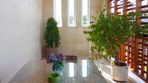 A room with a glass table, potted plants, and a view through a window with blinds. - VIP Green Studio Apartment Seminyak (Kuta, Badung)