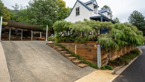 A two-story house with a sloped roof and a covered driveway. - BlueMill Cottage Bright - The Complete Luxury Getaway (Bright)