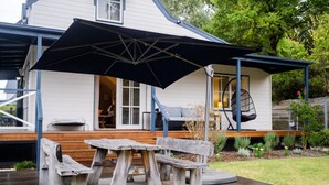 A house with a porch, a swing chair, and a table with benches. - BlueMill Cottage Bright - The Complete Luxury Getaway (Bright)