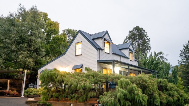 A modern two-story house with a sloped roof, large windows, and a covered porch area. - BlueMill Cottage Bright - The Complete Luxury Getaway (Bright)