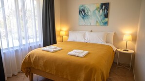 A hotel room with a bed, two bedside lamps, a painting on the wall, and a window with curtains. - Pet friendly accommodation on the Murray River (Murtho)