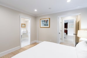 Un dormitorio con cama, una puerta que da a un baño y un pasillo.