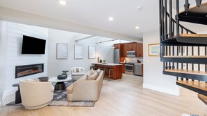 A spacious living area with a fireplace, a sofa, a coffee table, and a TV mounted on the wall. - 2 Bedrooms w/Loft  and  En-Suite Baths, Walk to Harbor (Newport)