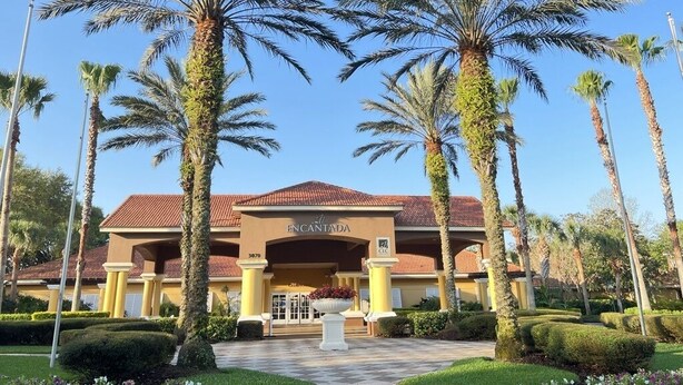A hotel entrance with palm trees, a red-tiled roof, and a sign reading "ENCANTADA." - Great home & location-private pool, forest view-near DISNEY & so much more! (Kissimmee)