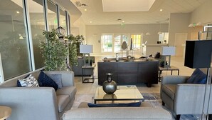 A modern lobby with sofas, a coffee table, and a reception desk. - Great home & location-private pool, forest view-near DISNEY & so much more! (Kissimmee)