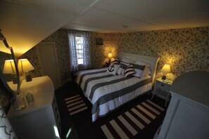 A bedroom with two beds, floral wallpaper, and bedside lamps.