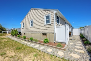 A two-story house with a sloped roof, a front porch, and a gravel pathway leading to the entrance.