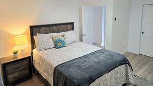 Quarto com cama, luminária de cabeceira, mesa de apoio e ventilador de teto.