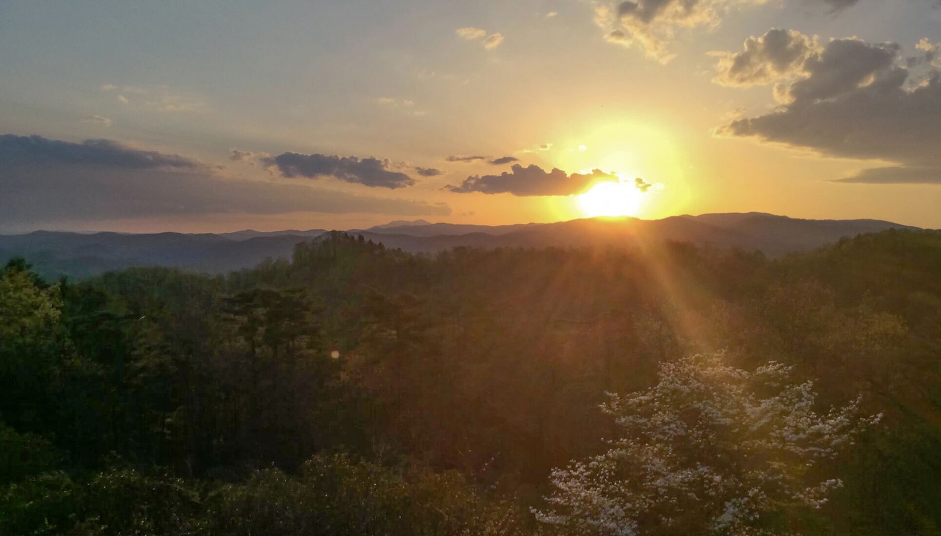 A sunset over a mountainous landscape with dense forest.
