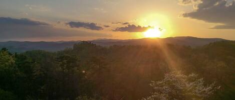 A sunset over a mountainous landscape with dense forest.