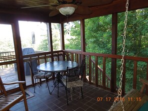 A covered outdoor patio with a round table and chairs, wooden railings, and a ceiling fan. - Romantic Leatherwood Mtn Log Home 19.3 acres /Panoramic View/Near Boone (Ferguson)