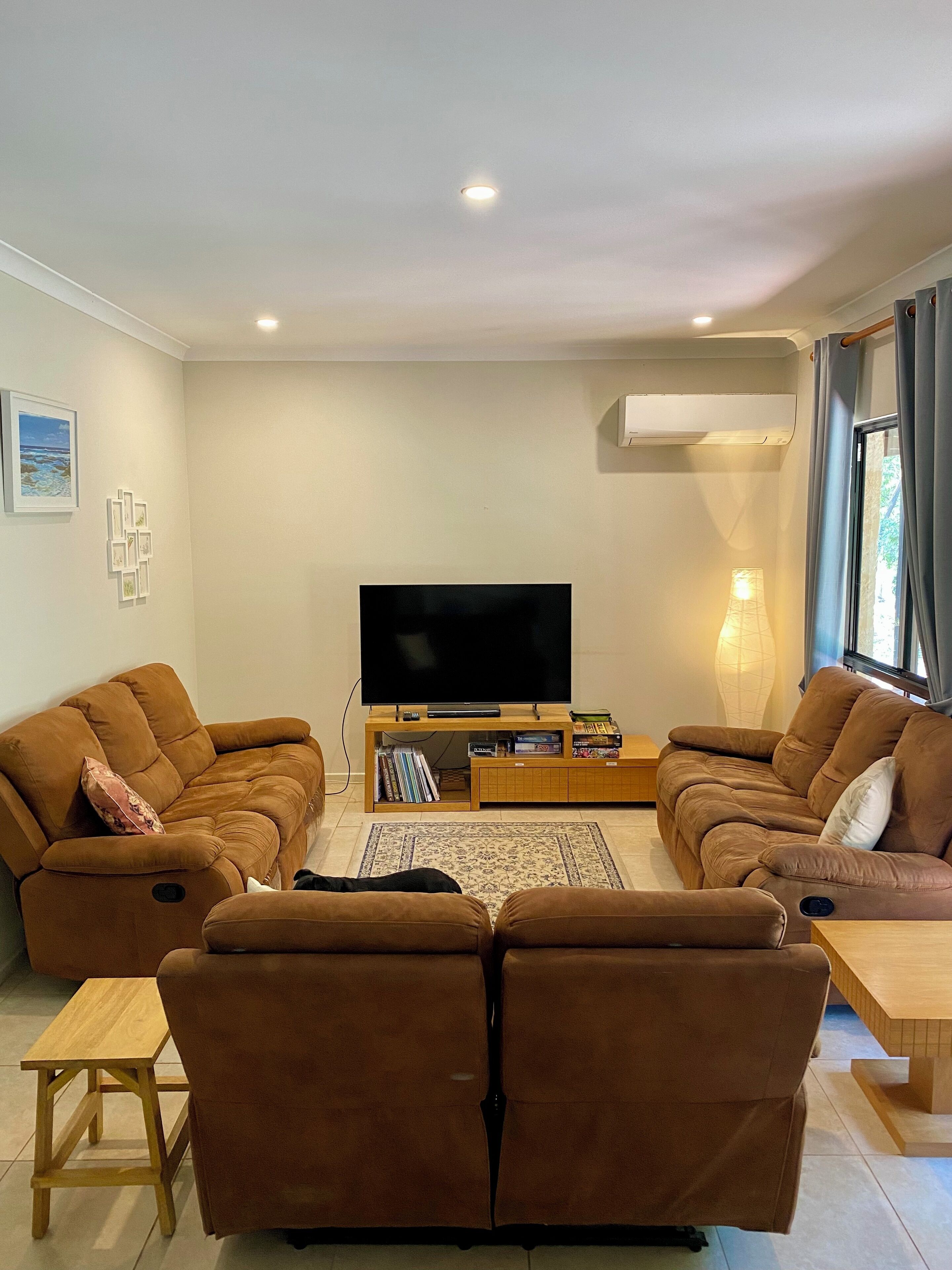 A living room with two brown sofas, a coffee table, and a flat-screen TV.