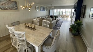 A spacious living area with a wooden dining table, white wicker chairs, a sofa, and a ceiling fan. - Direct Siesta Key Beachfront condo! (Siesta Key)