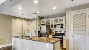 A modern kitchen with granite countertops, stainless steel appliances, and white cabinetry.