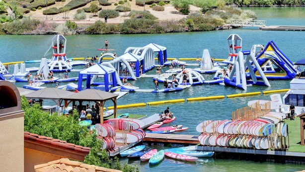 An outdoor water park with inflatable structures, paddle boats, and a dock with rowboats.
