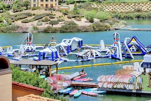 Un parc aquatique en plein air doté de structures gonflables, de pédalos et d’un quai avec des barques à rames.