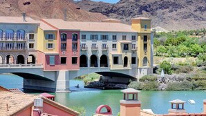 A multi-story building with balconies and a bridge over a river.