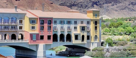 A multi-story building with balconies and a bridge over a river.