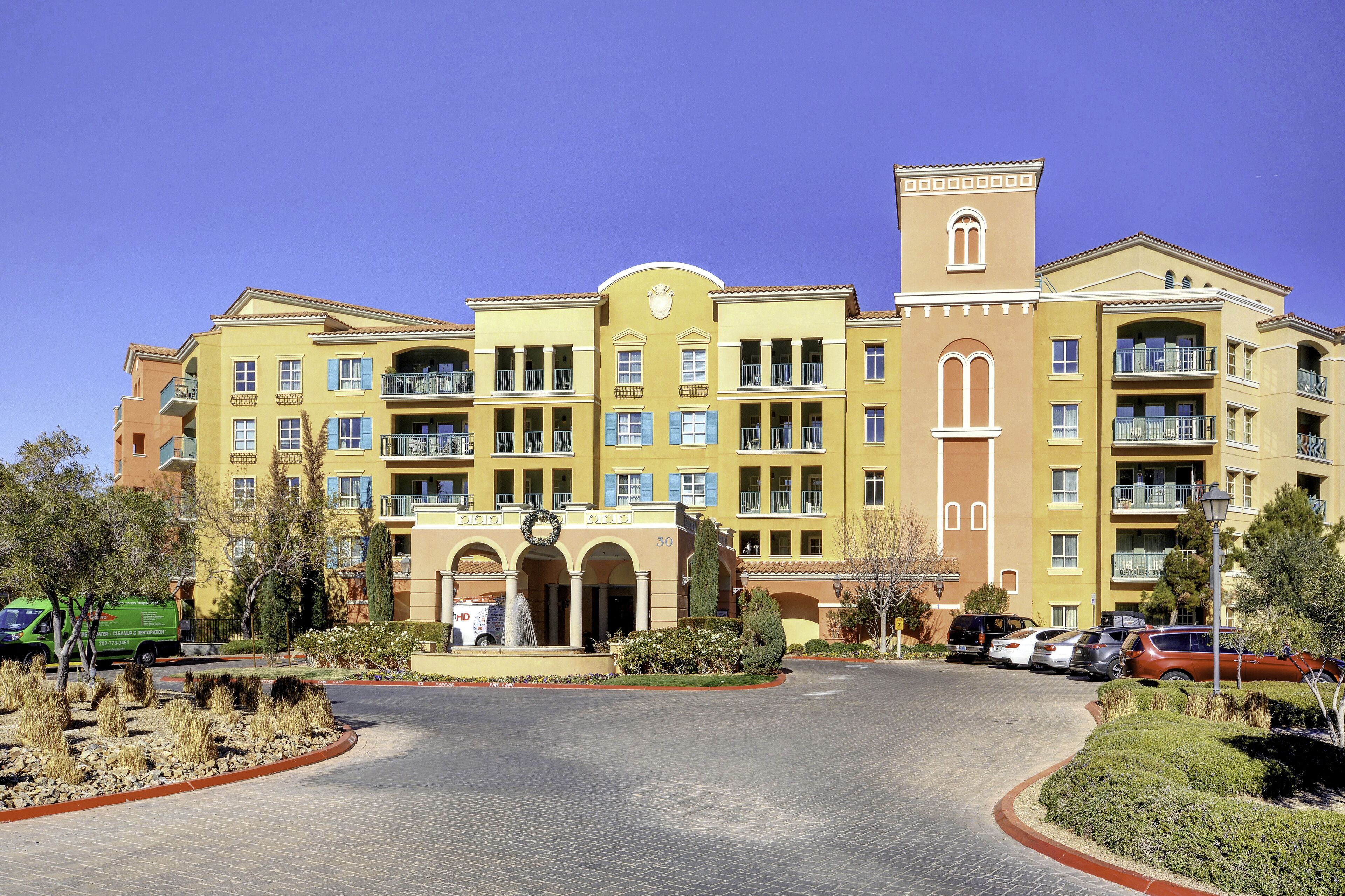 A multi-story hotel with a central courtyard, balconies, and a fountain.