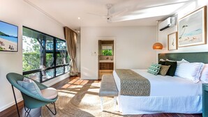 A modern bedroom with a large window, a bed, a chair, and a view of a beach. - Point Blue, Beautiful House on Hamilton Island (Hamilton Island)