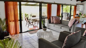 Ein Wohnzimmer mit grauem Sofa, einem runden Couchtisch und einem Essbereich mit Tisch und Stühlen.