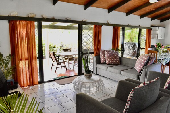 A living room with a grey sofa, a round coffee table, and a dining area with a table and chairs.