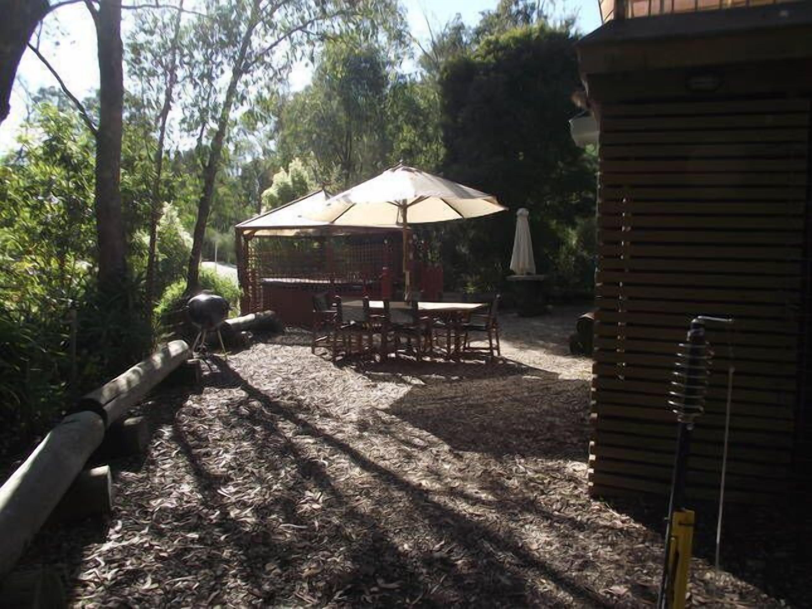 An outdoor patio area with a covered seating area, a table, and chairs.