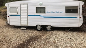 Ein weißer Wohnmobil mit blauem Streifen, einem kleinen Fenster und einer Tür.