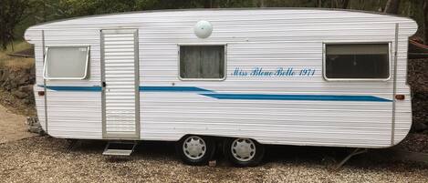 A white RV with a blue stripe, a small window, and a door.