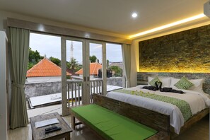 A hotel room with a balcony, a bed with green and white bedding, a wooden headboard, and a stone accent wall.