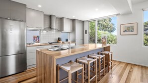 A modern kitchen with a central island, bar stools, and a large window. - Sirocco Roof Top Deck Pet Friendly in Aireys Inlet (Aireys Inlet)