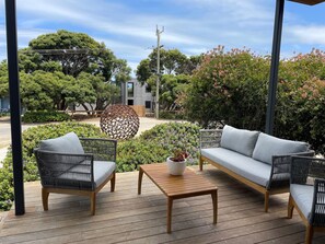 An outdoor patio with wicker furniture, a wooden table, and a decorative sphere.