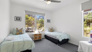 A bedroom with two beds, a ceiling fan, and large windows offering a view of the outdoors. - Sirocco Roof Top Deck Pet Friendly in Aireys Inlet (Aireys Inlet)
