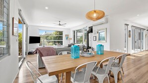A modern dining area with a wooden table, white chairs, and a ceiling fan. - Sirocco Roof Top Deck Pet Friendly in Aireys Inlet (Aireys Inlet)