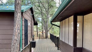 A wooden deck leading to a building with a green roof and a black railing. - Cozy Cabin: Deck, Hot Tub, Views & Starry Nights (Prescott)