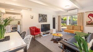 Un salon moderne avec un canapé, un fauteuil rouge, une table à manger et un meuble pour la télévision.