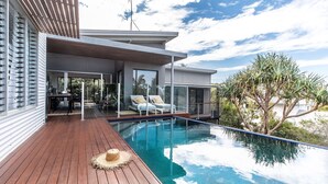 Ein modernes Haus mit Swimmingpool, einer Terrasse und einem wintergartenartigen Anbau.