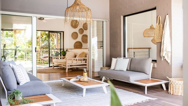 Ein modernes Wohnzimmer mit grauem Sofa, weißem Couchtisch und einer Hängeleuchte aus Korbgeflecht.